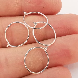 Könnte beinhalten: Vier silberne Creolen, jede mit einem einfachen runden Design, werden auf einer Hand gezeigt.