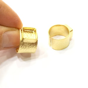 May include: Two gold-toned rings with a square bezel setting. The rings are made of metal and have a hammered texture.