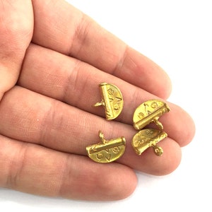 May include: Four gold-toned metal buttons with a decorative design. The buttons are half-round and have a small loop on the back.
