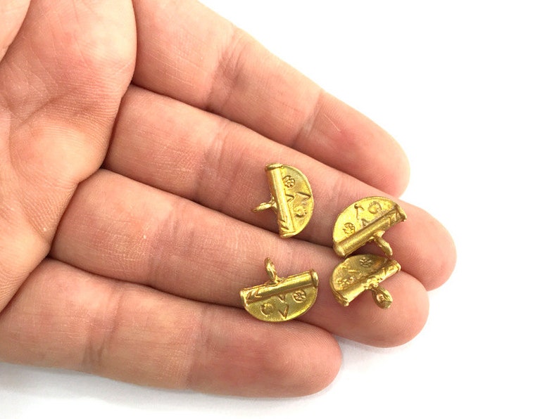 May include: Four gold-toned metal buttons with a decorative design. The buttons are half-round and have a small loop on the back.