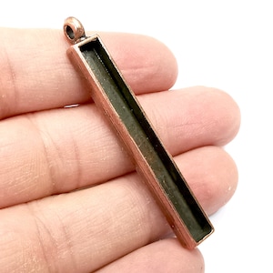 May include: A copper-toned metal pendant with a rectangular open space for resin or other materials. The pendant has a loop at the top for attaching to a chain or cord.