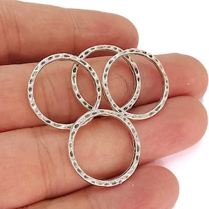 May include: Four silver-toned metal rings with a hammered texture. The rings are stacked on top of each other.