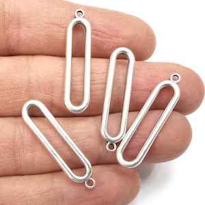 May include: Four silver-toned metal oval-shaped pendant charms with a jump ring at the top. The charms are open on the sides.