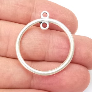 May include: Silver-toned metal circle pendant with two small loops at the top.