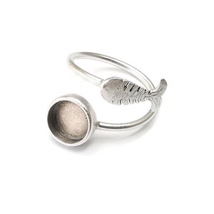 May include: Silver ring with a round bezel and a fish design. The bezel is empty and ready to be filled with a cabochon.