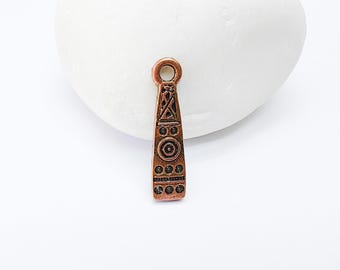 May include: A copper-colored pendant with a detailed geometric design. The pendant is shaped like a long, narrow rectangle with a loop at the top for attaching to a chain or cord.