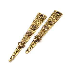 Puede incluir: Dos piezas decorativas de metal dorado con intrincados patrones y un diseño en forma de diamante en la parte inferior.