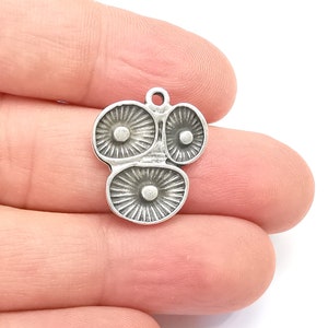 Pode incluir: Berloque de prata com um design de três cogumelos estilizados. O berloque tem um laço na parte superior para prender a um colar ou pulseira.