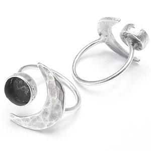 May include: Two silver crescent moon rings with a round bezel setting for a stone. The rings are open and adjustable.