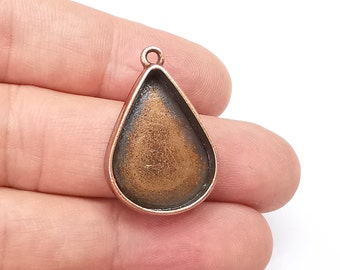 May include: A copper-toned metal pendant with a teardrop-shaped opening for a cameo or other embellishment. The pendant has a loop at the top for attaching a chain or cord.