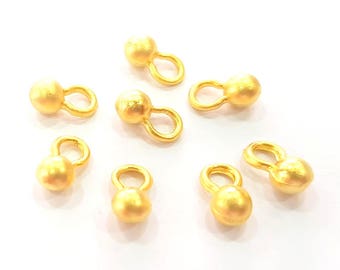 May include: Seven gold-toned metal ball and loop charms. Each charm features a round ball with a small loop attached.