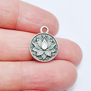 Puede incluir: Encanto de plata con un diseño detallado de flor de loto. El encanto tiene un bucle en la parte superior para sujetarlo a un collar o pulsera.