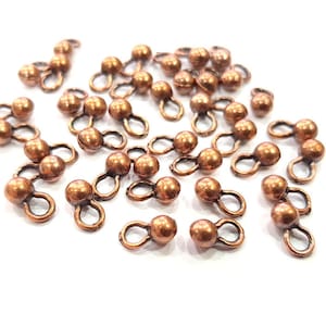 May include: A group of 20 copper-colored metal bead caps with two loops on each. The bead caps are about 1 cm in diameter.