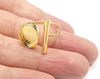 May include: Gold ring with a round, open-ended bezel and a vertical bar with a small clear stone. The ring is on a finger.