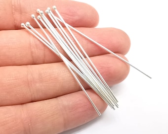 May include: A close-up of a pile of silver-colored head pins. The pins are about 2 inches long and have a round head.