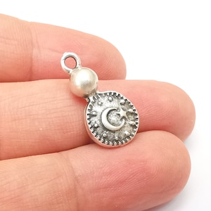 Puede incluir: Encanto de plata con un diseño de luna creciente y estrella. El encanto tiene una pequeña cuenta en la parte superior para sujetarlo a un collar o pulsera.