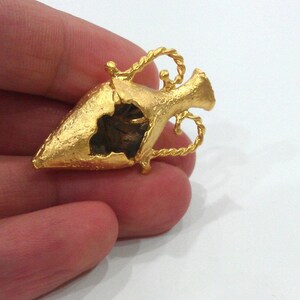 May include: A gold-colored, detailed, decorative, open-work,  miniature,  vaseshaped pendant.