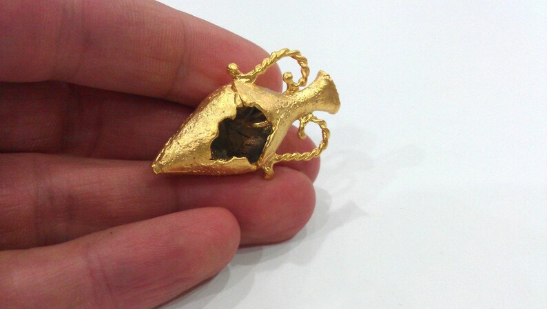 May include: A gold-colored, detailed, decorative, open-work,  miniature,  vaseshaped pendant.