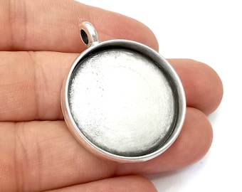 May include: Silver round pendant with a smooth, white surface and a loop at the top for attaching a chain.