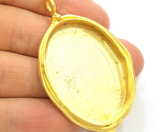 May include: Gold-toned oval pendant with a smooth, shiny surface. The pendant has a loop at the top for attaching a chain.