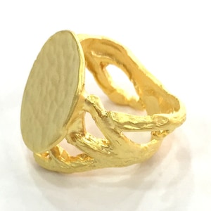 Op de afbeelding: Een gouden ring met een getextureerde, ovale bovenkant en een delicate, opengewerkte band. De band is ontworpen om te lijken op takken of twijgen.