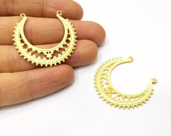 May include: Two gold-colored crescent moon-shaped jewelry components. Each component features an intricate openwork design with a series of small, raised dots along the outer edge and decorative cutouts. The components have small loops at the top for attachment.