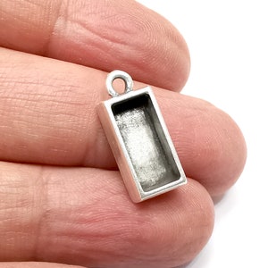 May include: Silver pendant with a rectangular bezel for a cameo or other small object. The pendant has a loop at the top for attaching to a chain.