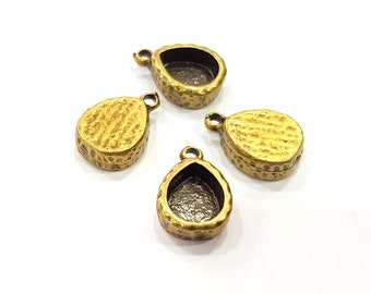 May include: Four antique brass-colored pendant trays in various shapes: teardrop, oval, and round. Each has a textured surface and a small loop for attaching to a chain or cord. The trays have a recessed area for setting a stone or other embellishment.