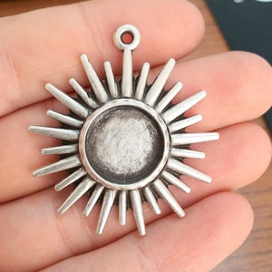 Peut inclure: Charme de pendentif en argent en forme de soleil avec un centre rond ouvert. Le soleil a une finition texturée et vieillie.