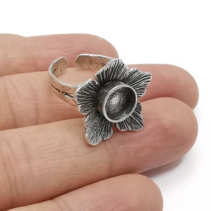 Op de afbeelding: Zilveren ring met een bloemmotief. De bloem heeft een rond, open midden dat kan worden gebruikt om een klein voorwerp te houden, zoals een steen of een bedel.