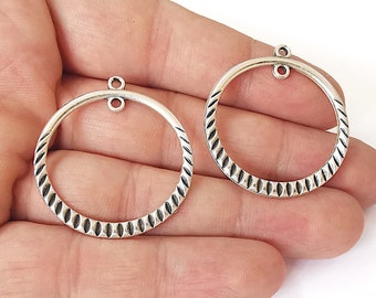 May include: Two silver-toned metal circle pendant charms with a textured design and a loop at the top.
