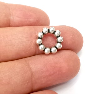 May include: Silver bead ring charm with a circular shape and a smooth finish.