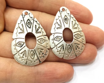 May include: Two silver teardrop-shaped earring charms with a geometric design. The charms have a hole at the top for attaching to earrings.