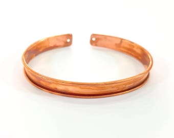 May include: A copper bracelet with a hammered finish and a slightly rounded shape.