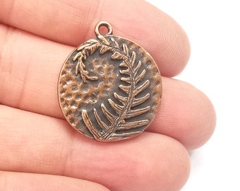 May include: A copper-colored pendant featuring a fern frond design. The pendant is round and has a textured surface.
