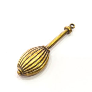 May include: A gold-toned metal charm shaped like a traditional Indian musical instrument, the tanpura. The charm has a long, thin handle and a rounded, ribbed body.