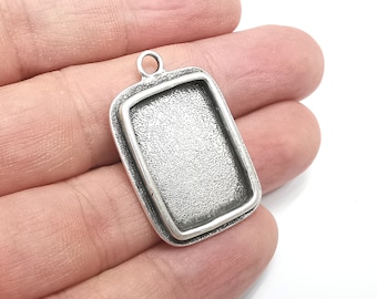 May include: Silver-toned pendant with a rectangular frame, perfect for adding a personalized touch to jewelry projects.