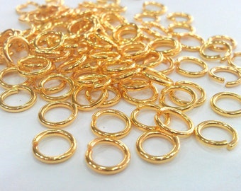 May include: A large pile of gold-colored jump rings. The rings are small and round, and they are all linked together.