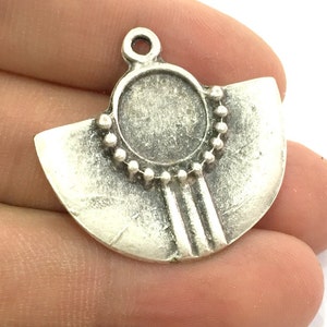 May include: Silver-toned metal pendant with a circular cutout and a fan-shaped design. The pendant has a beaded border and three vertical lines.