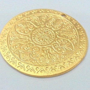 Peut inclure: Un pendentif en m&eacute;tal dor&eacute; avec un motif en relief complexe. Le pendentif est rond et poss&egrave;de un trou en haut pour l'accrocher.