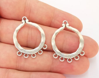 May include: Two silver-toned metal earring hoops with a hammered texture and five small loops hanging from the bottom of each hoop.