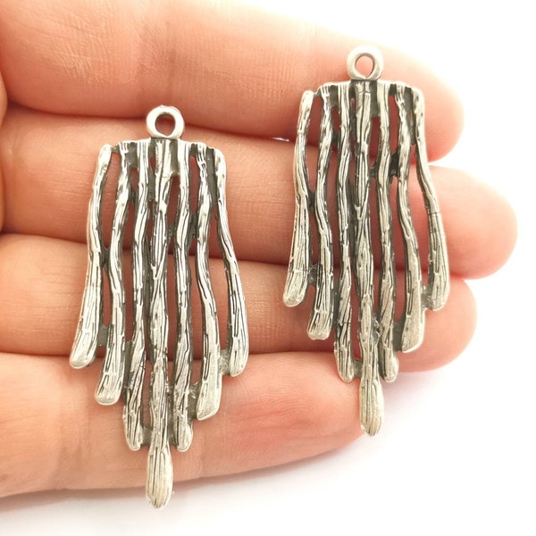 May include: Two silver metal pendant charms with a textured, twig-like design. The charms are shaped like a teardrop and have a loop at the top for attaching to jewellery.