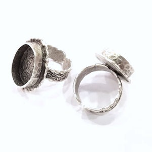 May include: Two silver rings with a textured finish. The rings have a round, open setting for a stone or cabochon.