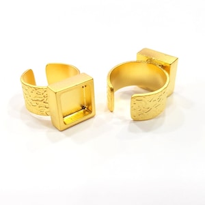 Op de afbeelding: Twee verstelbare gouden ringen met vierkante bezels. De bezels zijn open en klaar om te worden gevuld met hars of andere materialen.
