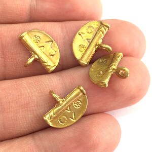 May include: Four gold-colored metal charms shaped like half circles with a raised design and text. The charms have a loop on the back for attaching to a necklace or bracelet.