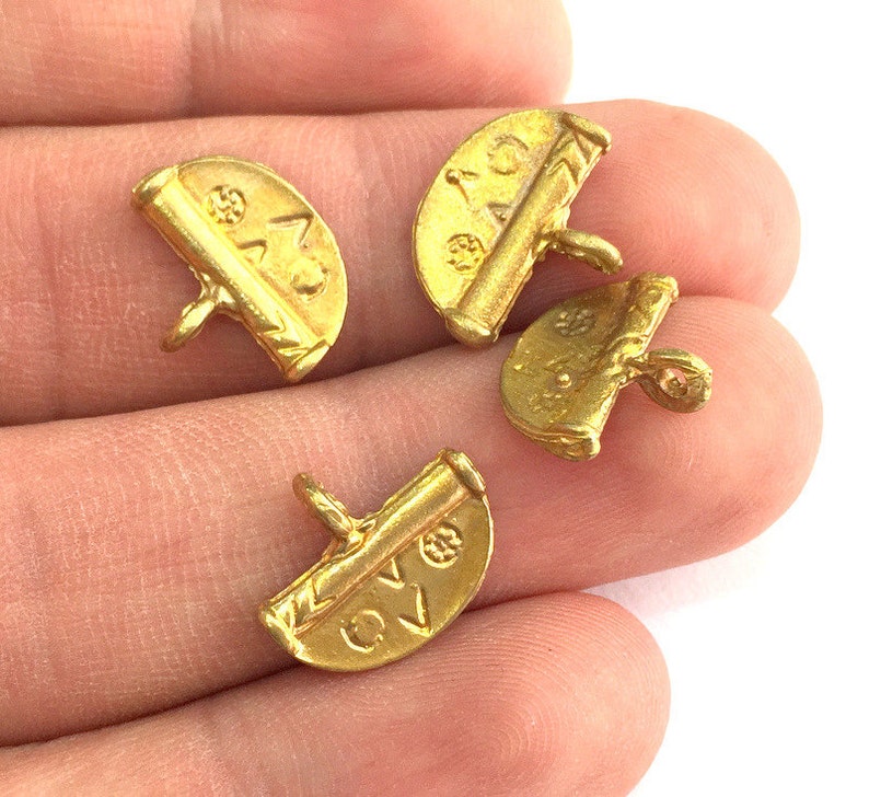 May include: Four gold-colored metal charms shaped like half circles with a raised design and text. The charms have a loop on the back for attaching to a necklace or bracelet.