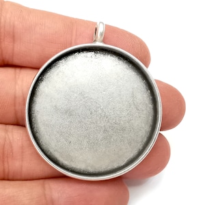 Può includere: Vassoio rotondo in argento per ciondolo, con una superficie liscia argentata. Il vassoio ha un anello nella parte superiore per appenderlo.