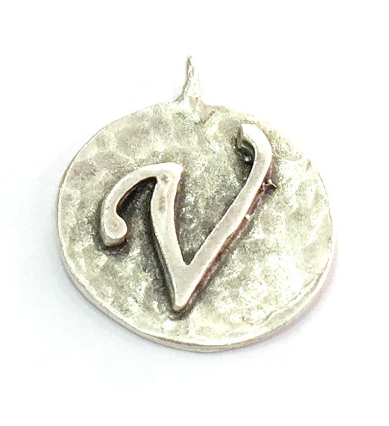 May include: Silver charm with a hammered finish and the letter V in a cursive font.