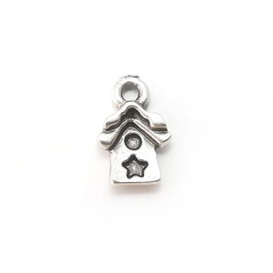 May include: Silver charm in the shape of a birdhouse with a star on the front.