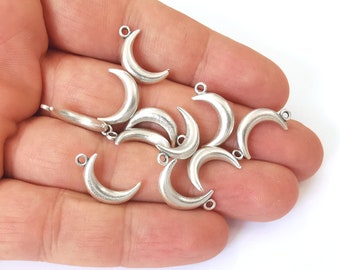 May include: A group of silver crescent moon charms with a loop at the top for attaching to jewelry or other crafts.